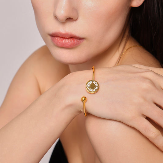 Closeup of 18k gold plated daisy sea shell stretch bangle on hand