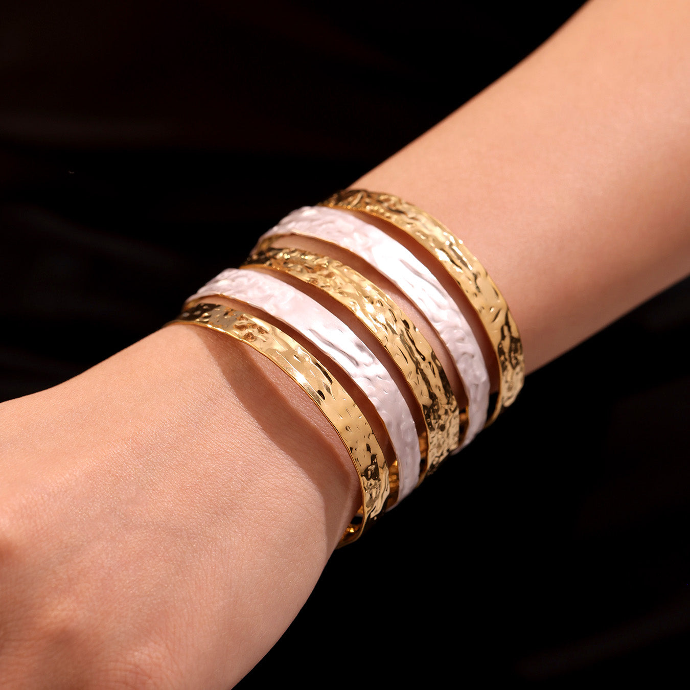 Closeup of stacked 18k gold plated oil drop color block open bangle, minimalist arm cuff