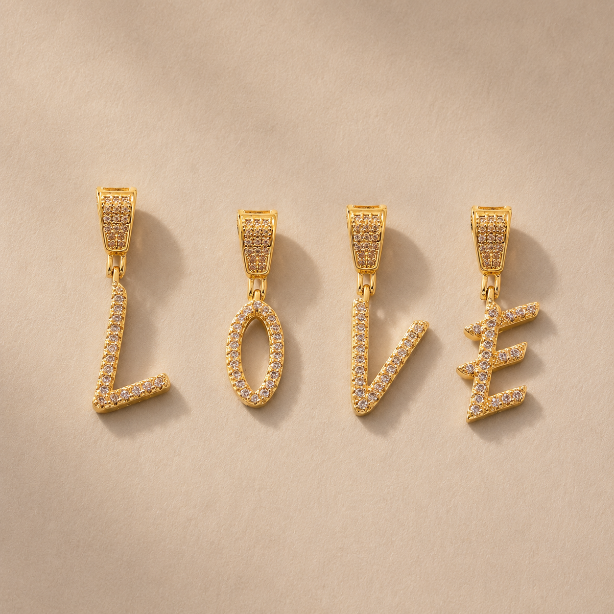 18K gold plated zircon LOVE letter pendant charms with sparkling clear stones on beige background