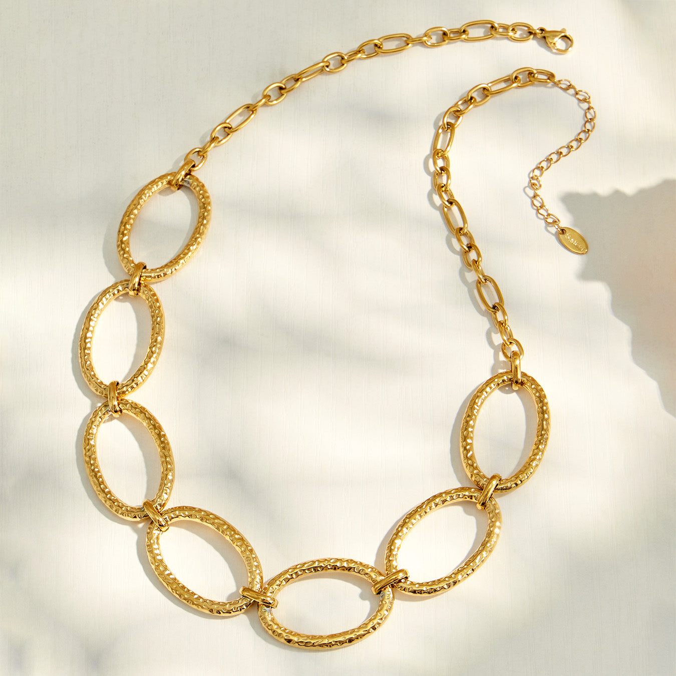18K PVD gold oval link necklace worn on a model with a black V-neck outfit