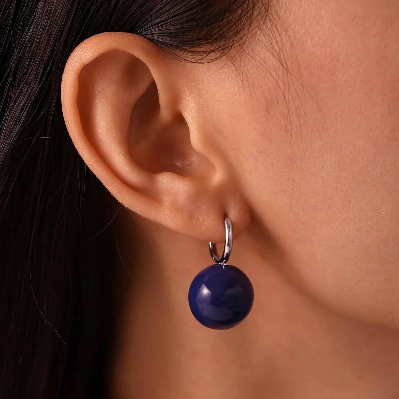 Side view of model wearing a navy ball drop earring with a steel-tone hoop