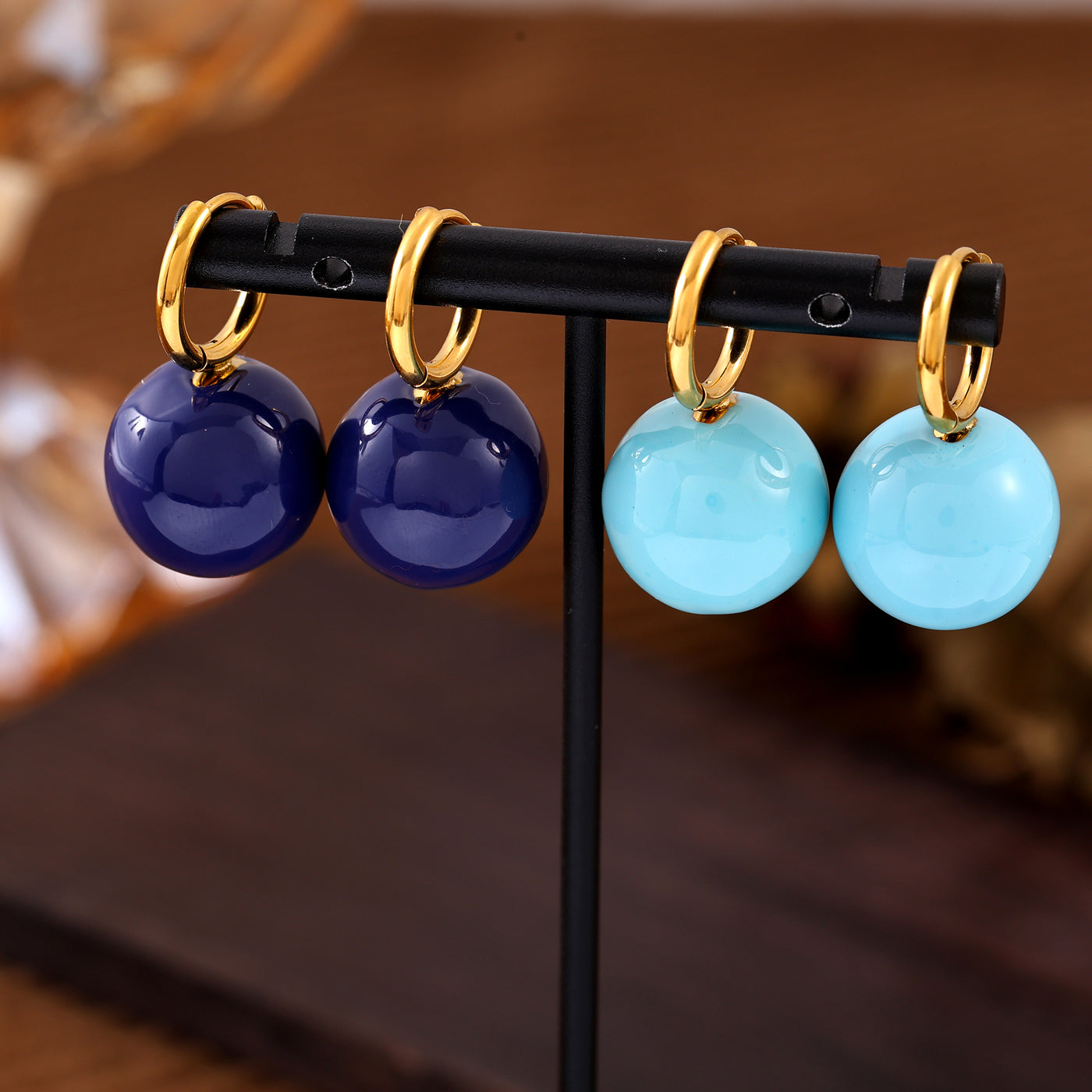 Navy and light blue ball drop hoop earrings displayed on a jewelry stand