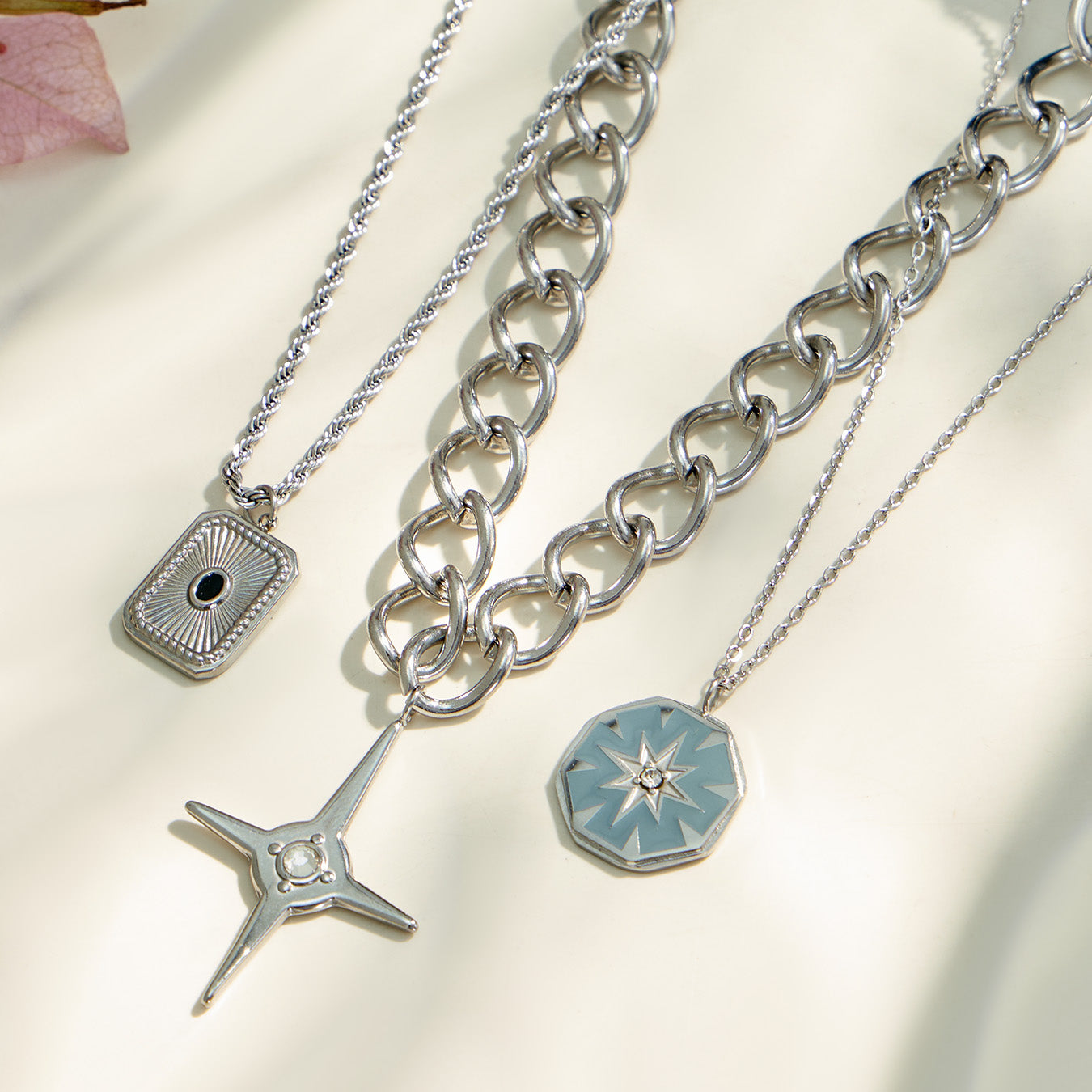 Close-up of square, starburst and four-point cross pendant necklaces with different chain styles