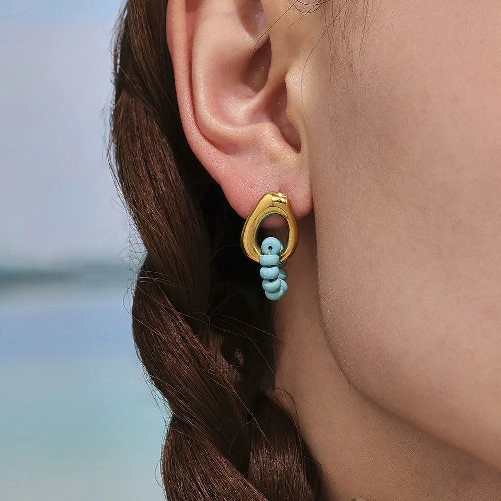 Side profile of model wearing waterproof 18K gold plated blue turquoise hoop earrings for sensitive skin.