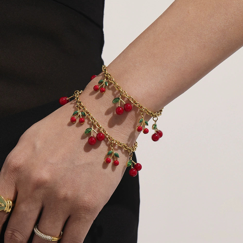 A delicate 18K gold plated cherry bracelet worn on a woman's wrist, featuring waterproof and nickel-free materials.