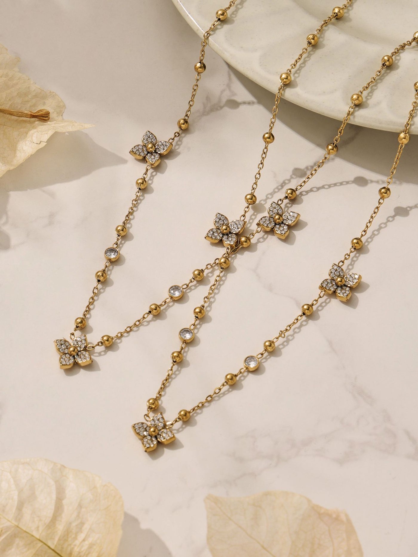Detailed look at the geometric chain bracelet with zircon flower charms, featuring a high-shine 18K gold finish.