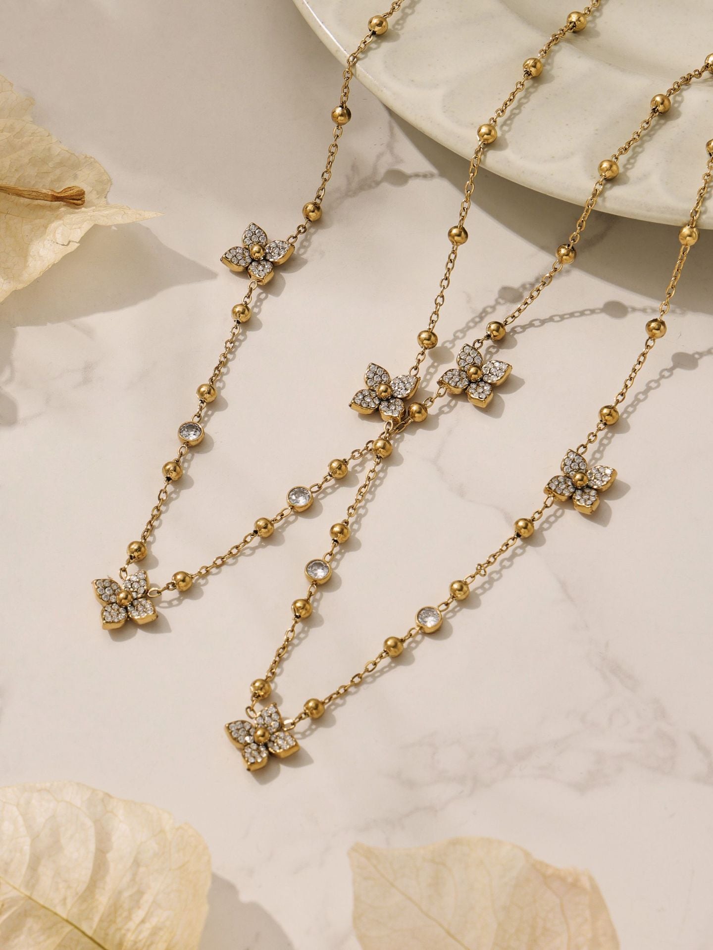 Detailed look at the geometric chain bracelet with zircon flower charms, featuring a high-shine 18K gold finish.