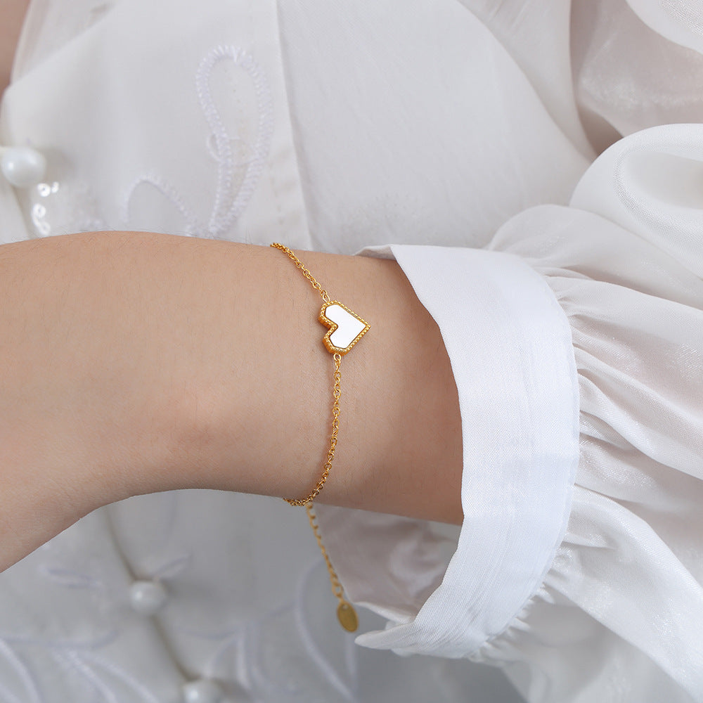 A dainty gold heart bracelet worn on a woman's wrist, made of waterproof 316L stainless steel.