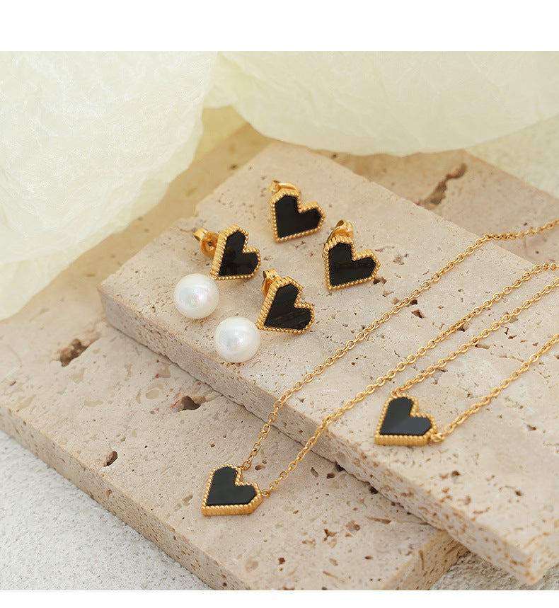 Multiple styles of heart-shaped earrings and necklaces displayed on a jewelry tray for wholesale selection.