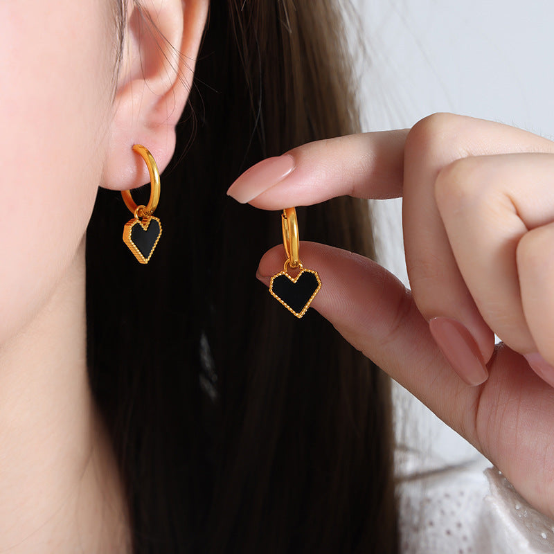 Model holding a pair of red heart-shaped stud earrings made of nickel-free 316L stainless steel.