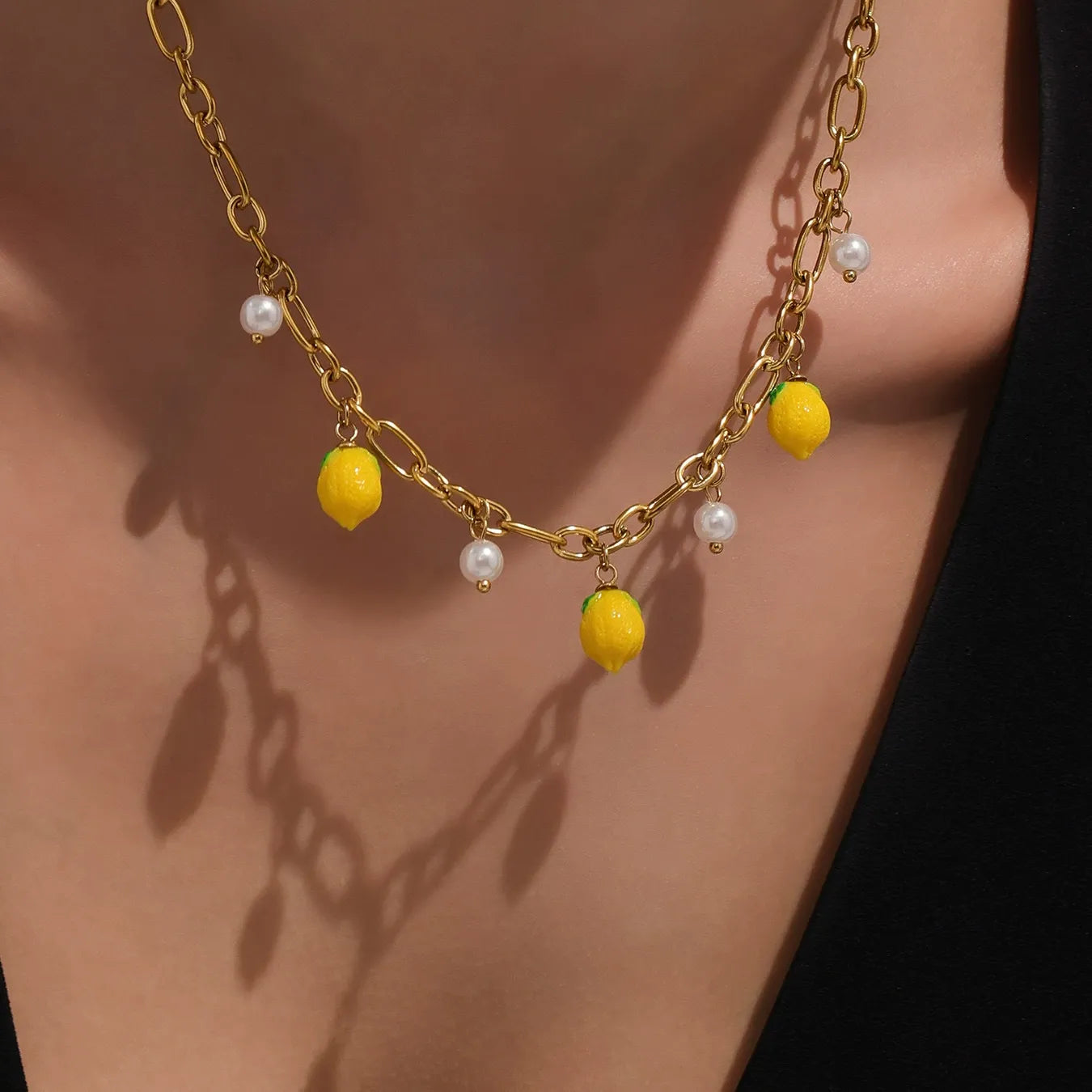 Close up of a model wearing the hypoallergenic gold lemon necklace with dainty shell pearls, showcasing its fresh summer style.