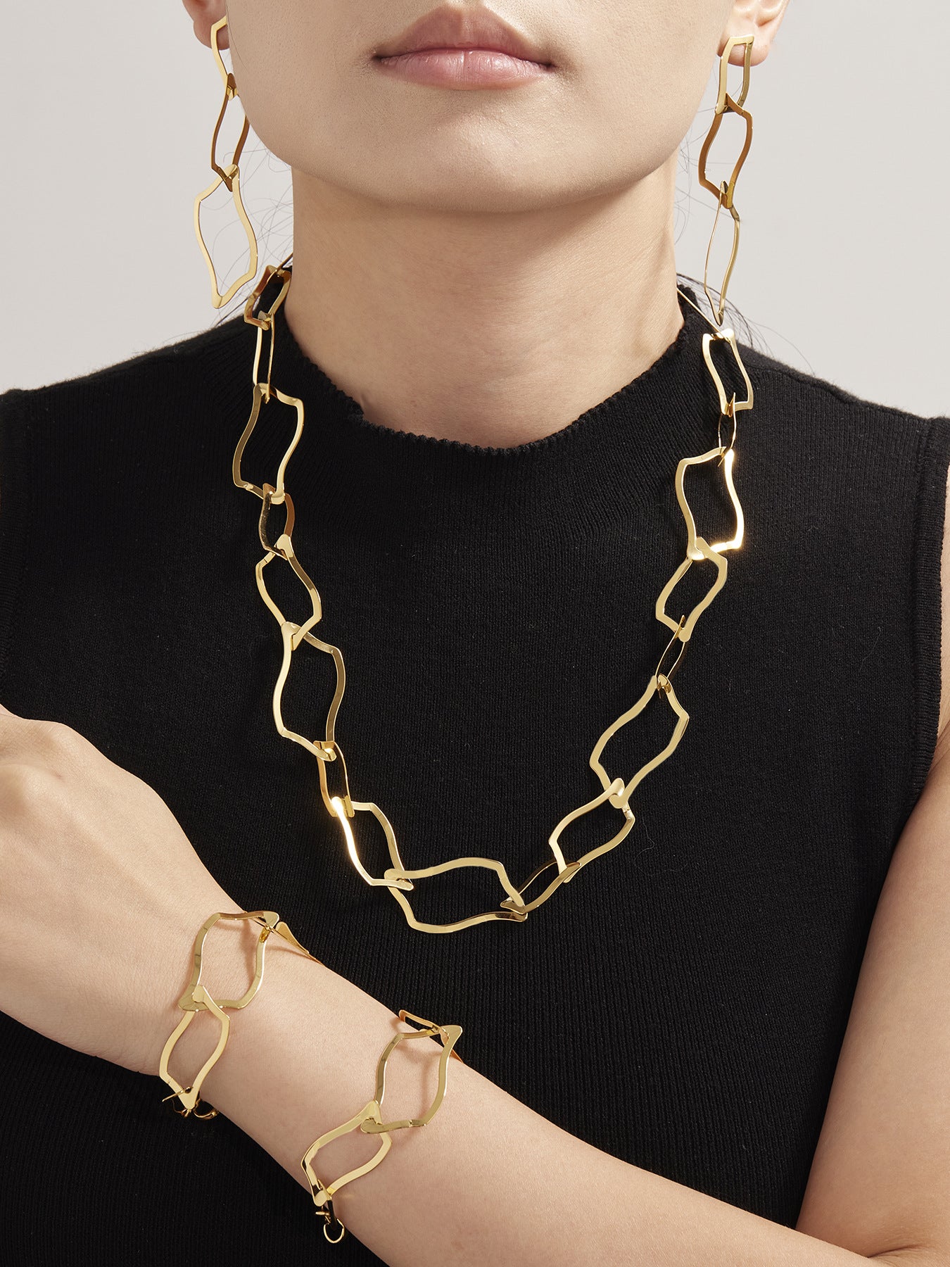 Close up of a woman styled with the 18K gold plated geometric jewelry collection, demonstrating its radiant finish on sensitive skin.