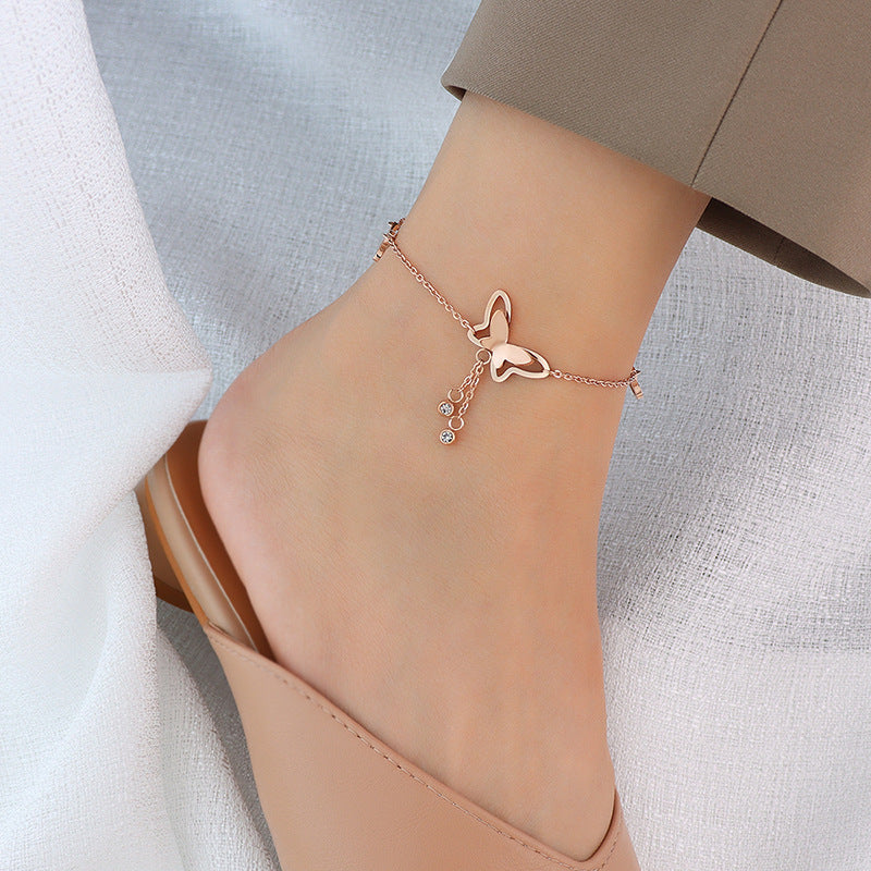 Close-up of butterfly charm and tassel detail on gold 316L stainless steel anklet, intricate design for boutique display