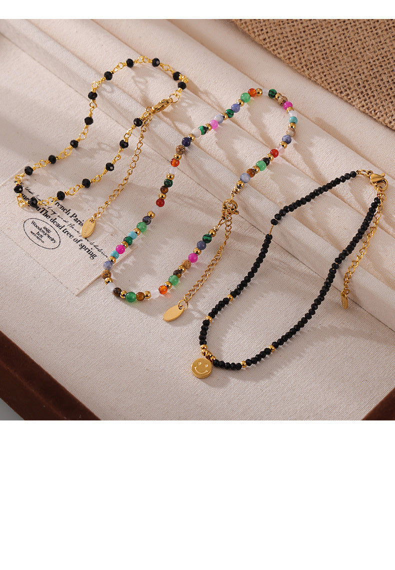 Top-down flat lay of multiple colorful natural stone beaded anklets on neutral background, 316L stainless steel construction and gold plating for sensitive skin
