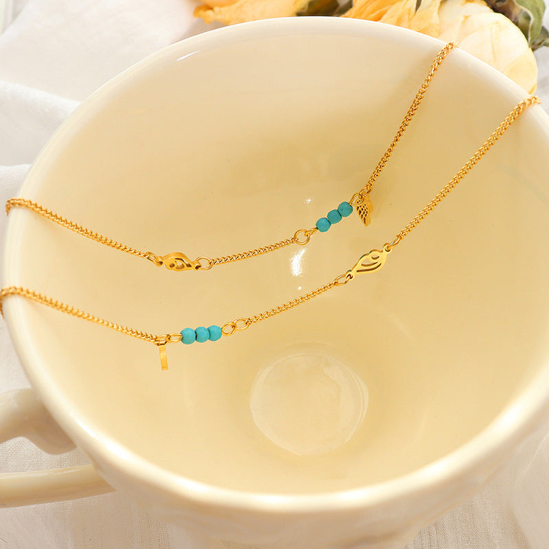Soft styled shot of gold turquoise wing anklet in warm decor, layered look and vibrant turquoise accent for boho summer aesthetic