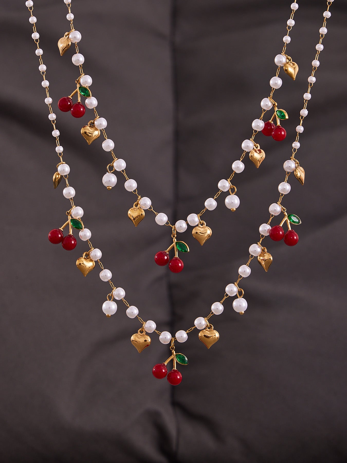High-quality 18K gold PVD plated beaded jewelry set featuring red cherries and pearls on a dark aesthetic background.