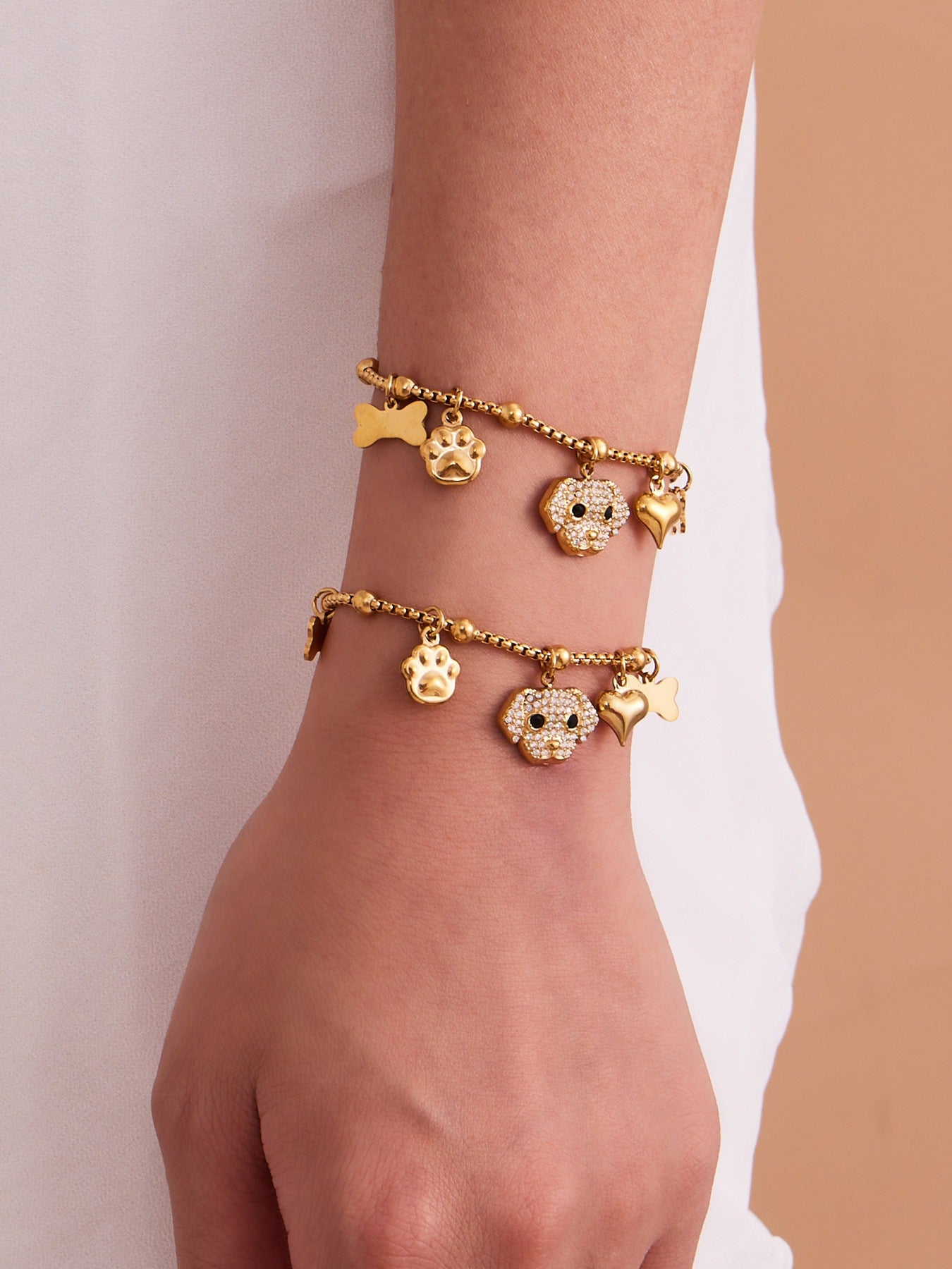 Model's hand showcasing gold dog charm bracelet and matching ring, 18K gold plated stainless steel, waterproof.