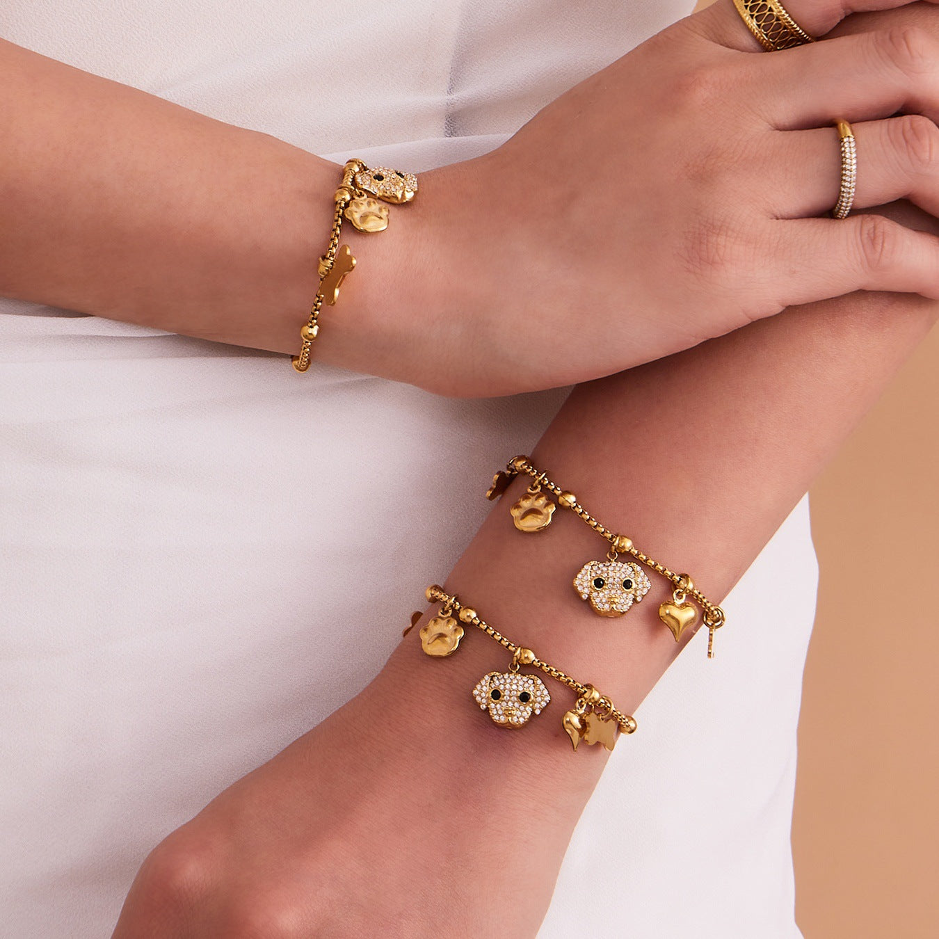 A woman wearing gold dog and bone charm bracelet made of 316L stainless steel, tarnish-resistant and hypoallergenic.