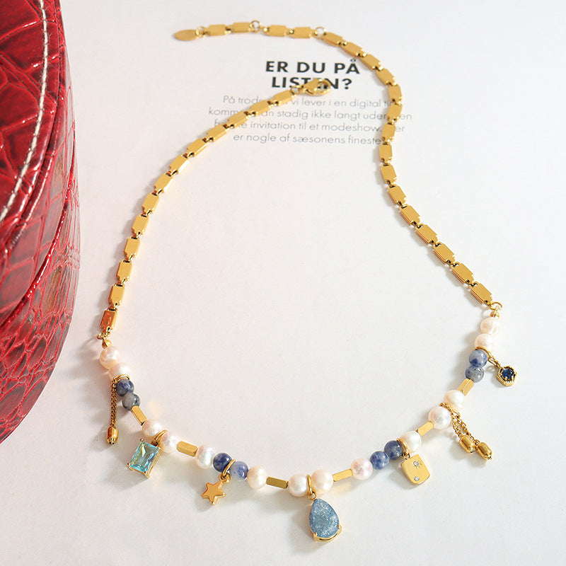 Flat lay of 316L stainless steel pearl charm necklace with mixed material design