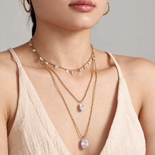 Gold zircon pendant and station necklaces layered on model