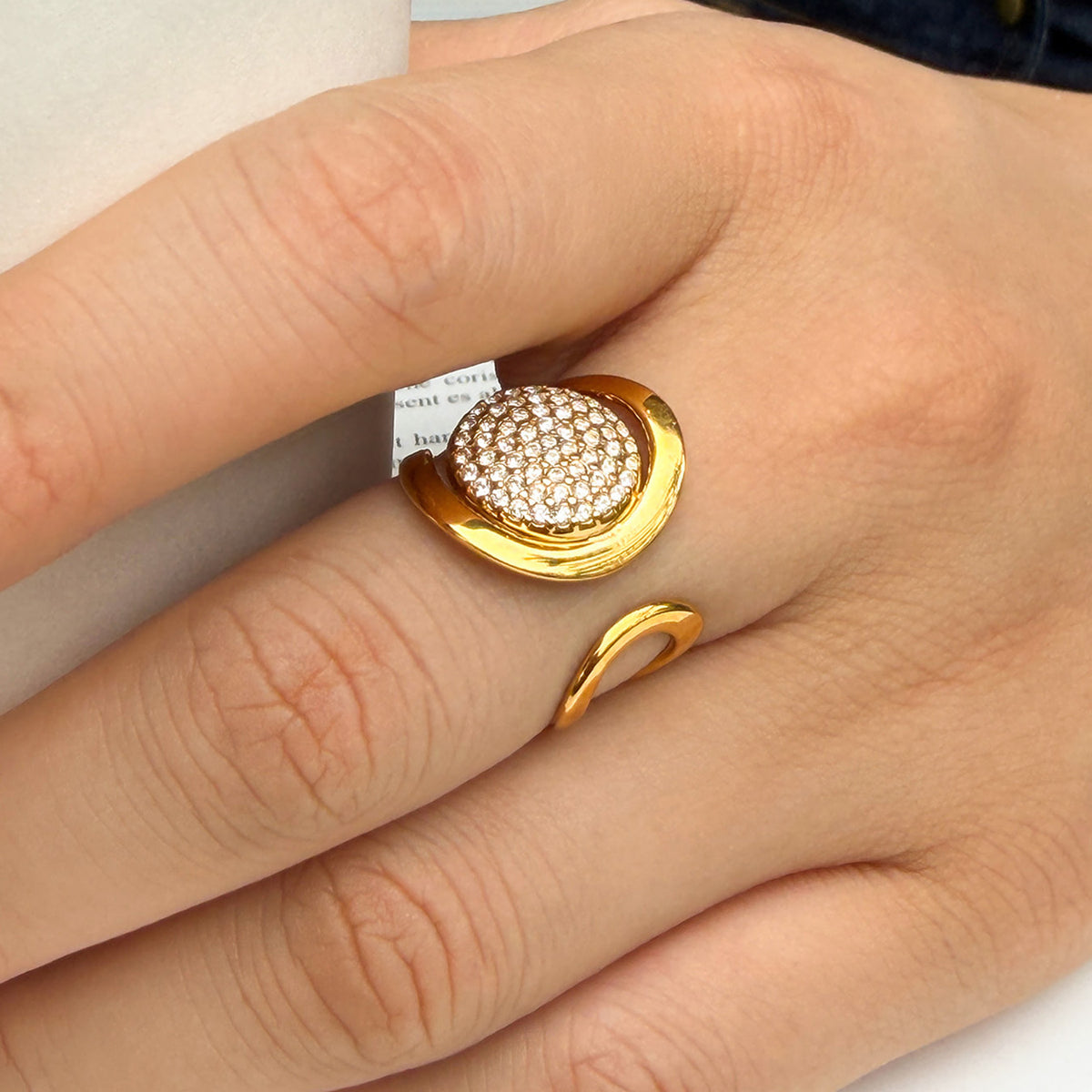 Gold pavé disc statement ring worn on a finger, highlighting the sparkling round centerpiece and open-band design