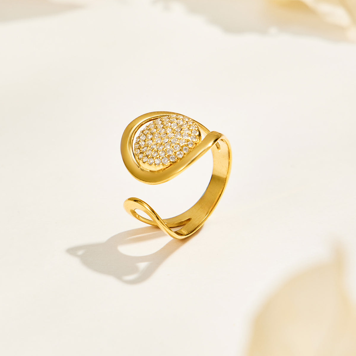 Gold pavé disc ring displayed on a neutral background, showing its raised round setting and asymmetrical open band