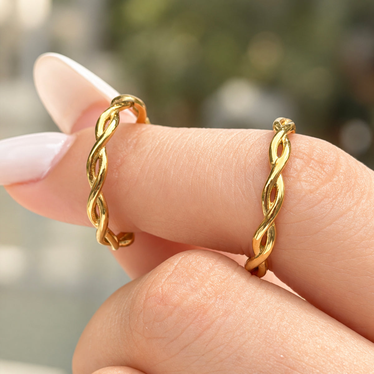 Two A451 gold-tone stainless steel twisted band rings displayed on a finger, showing their polished stone-free design