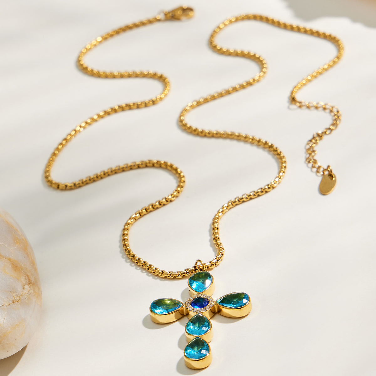 Gold-tone blue stone cross pendant necklace flat lay