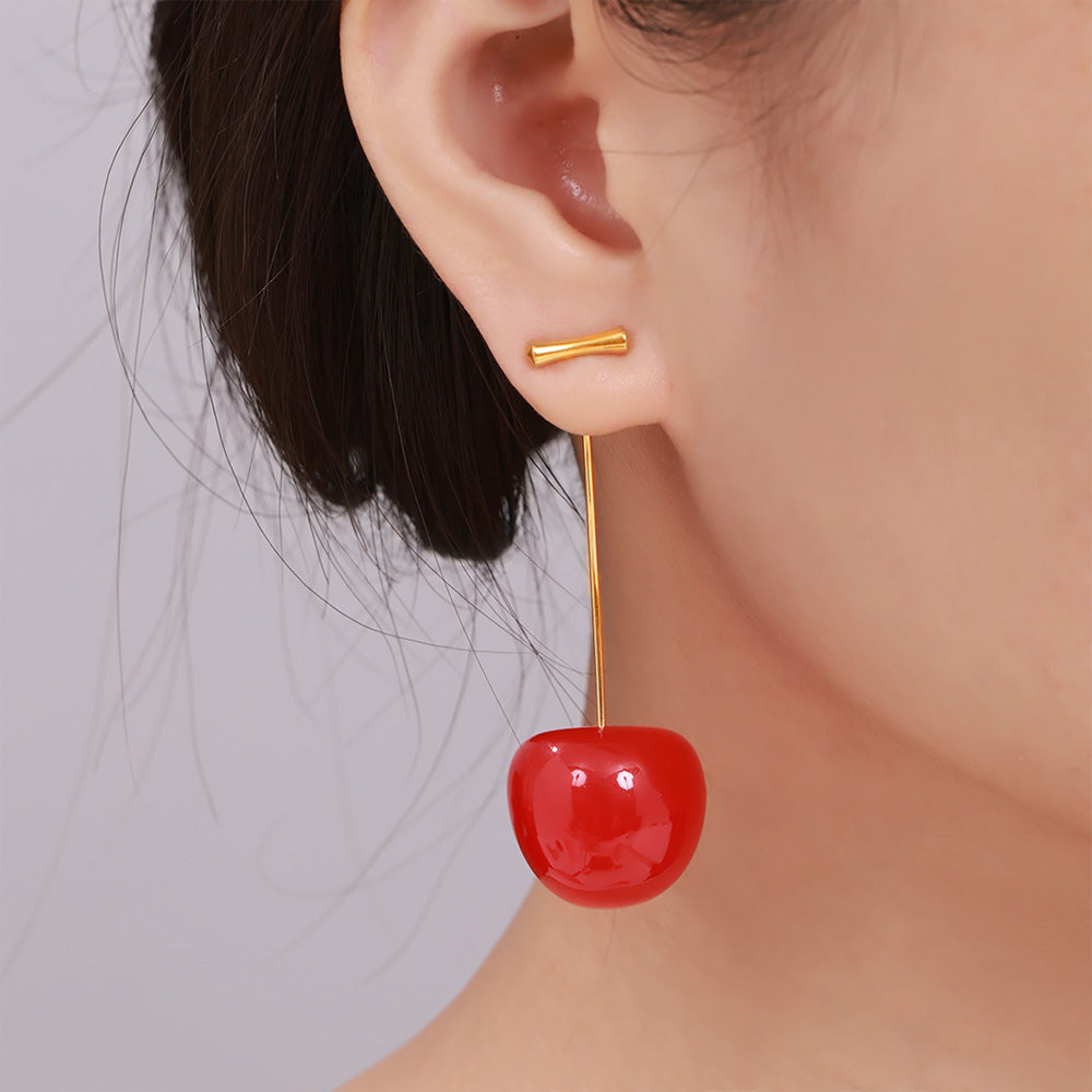 Bright red resin cherry dangle earrings worn on a model ear