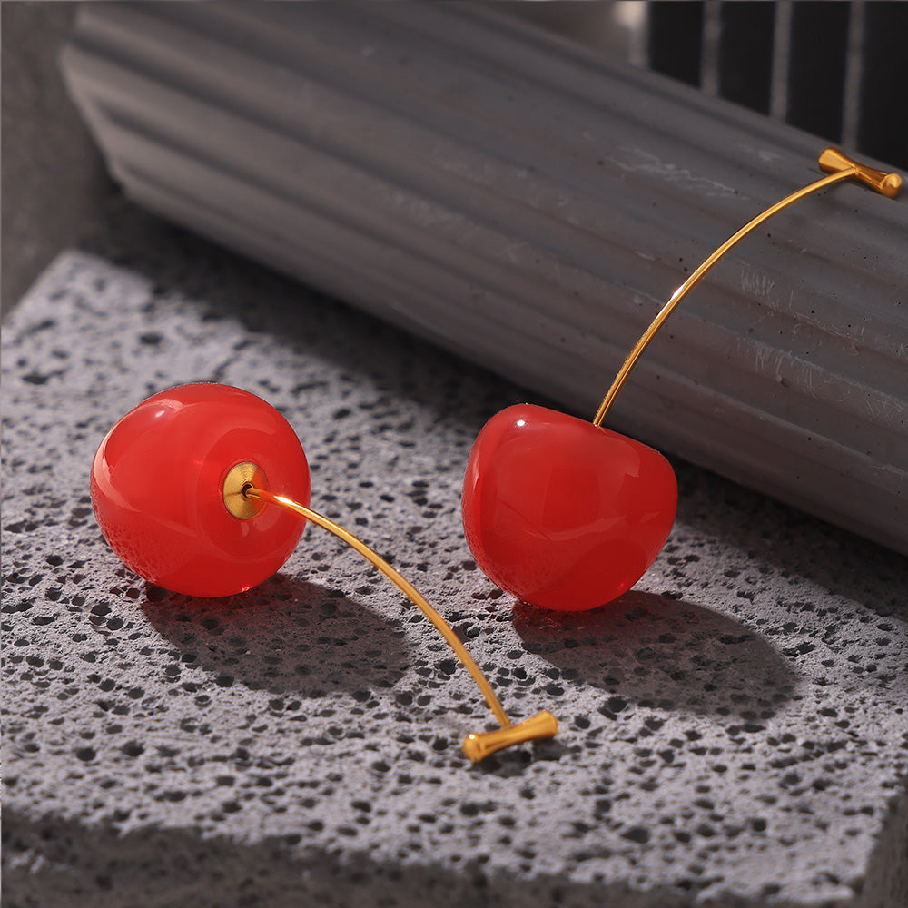 Bright red cherry drop earrings displayed on a black jewelry box