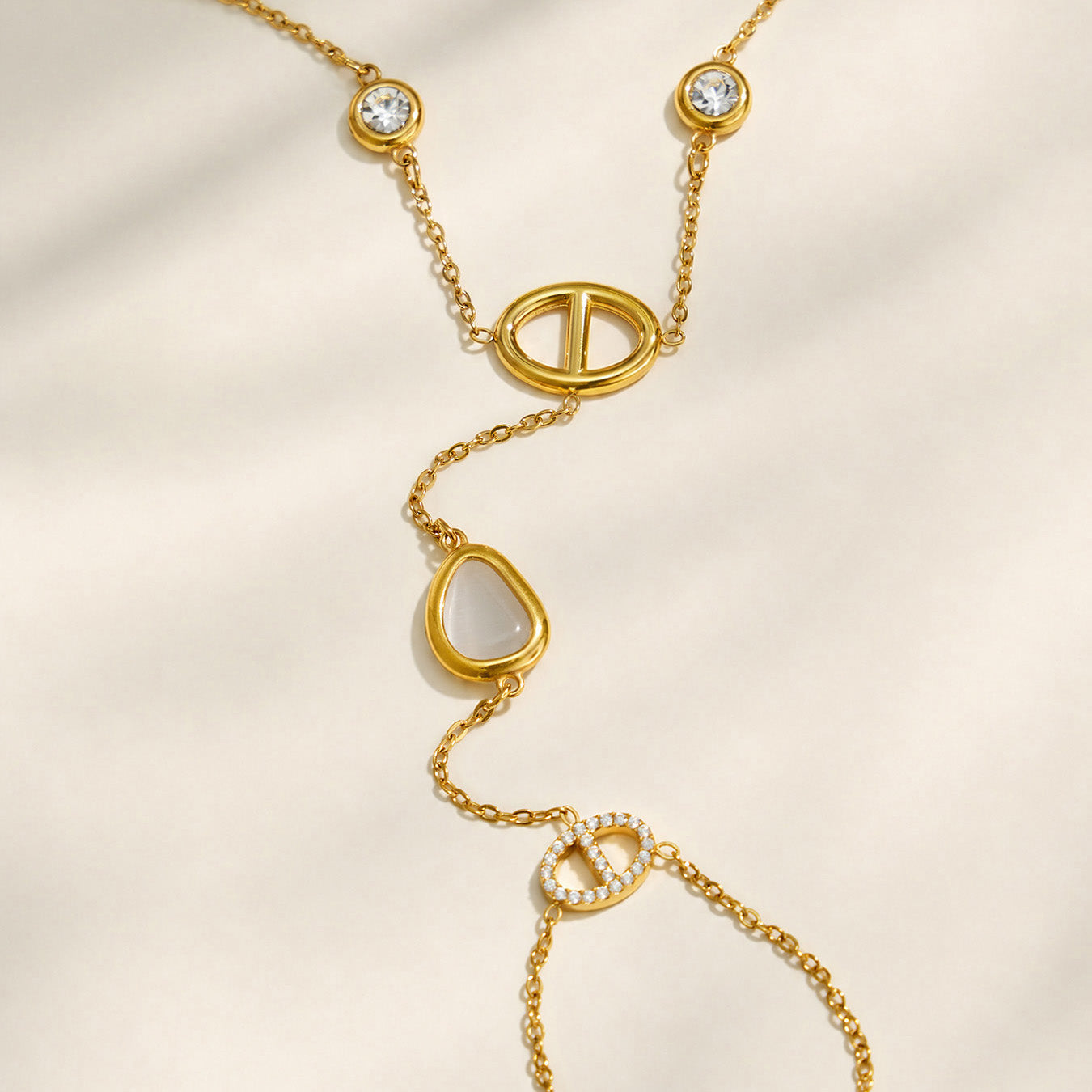 Close-up of white cat eye stones and geometric D-shaped links on a gold hand chain