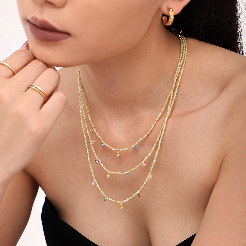 Close-up of a model wearing a colorful natural stone layered necklace with delicate gold chains