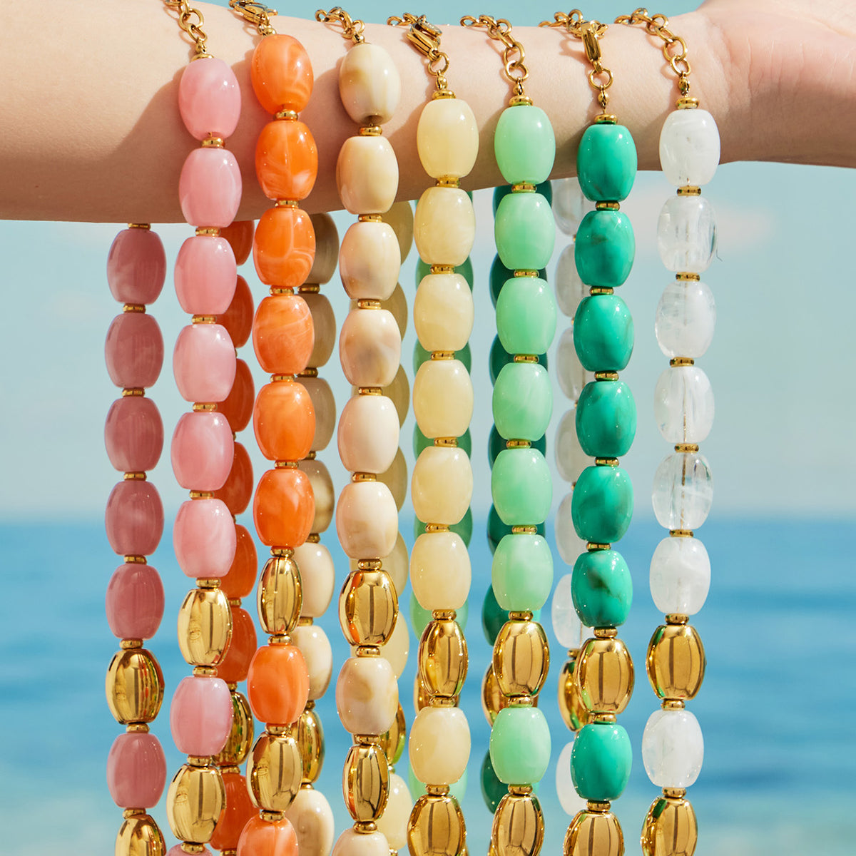 Colorful resin bead necklaces draped over an arm, showing seven colorways with gold-tone accents