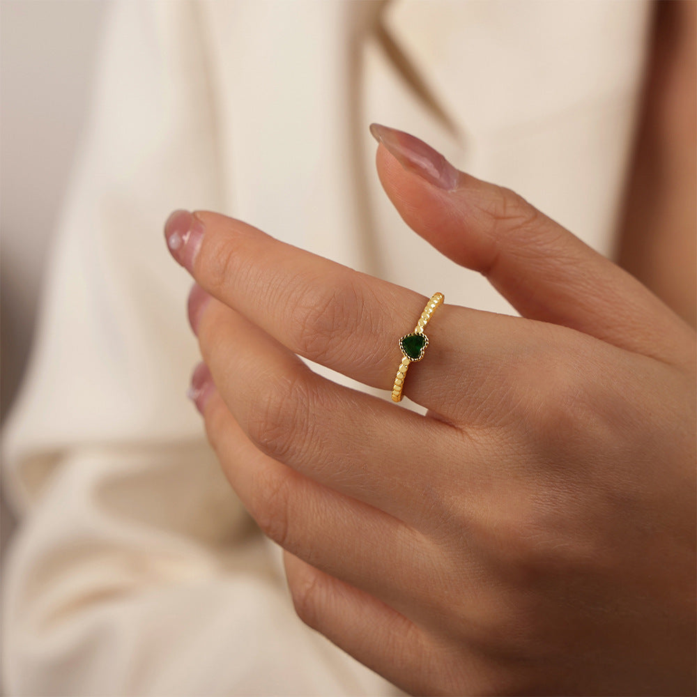 Model wearing a dainty gold-tone ring with a single green heart zircon stone