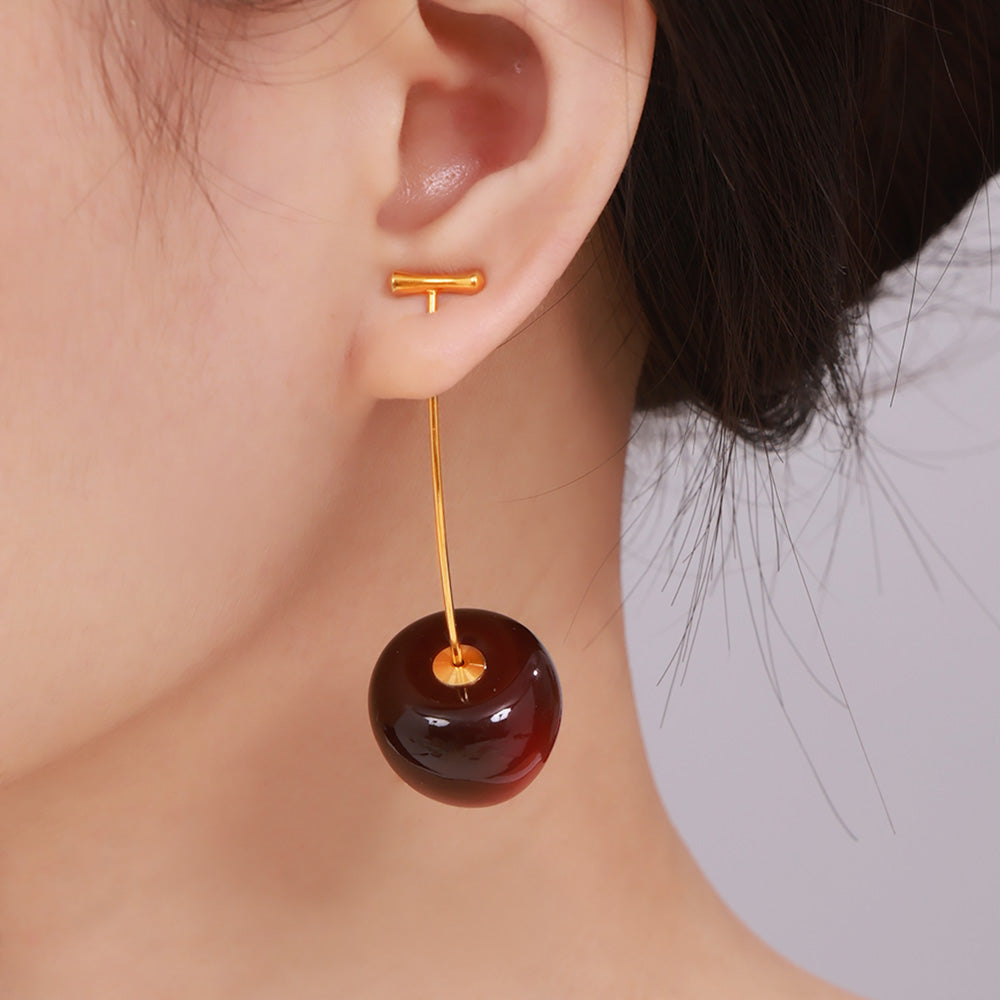 Side view of a model wearing dark burgundy resin cherry earrings