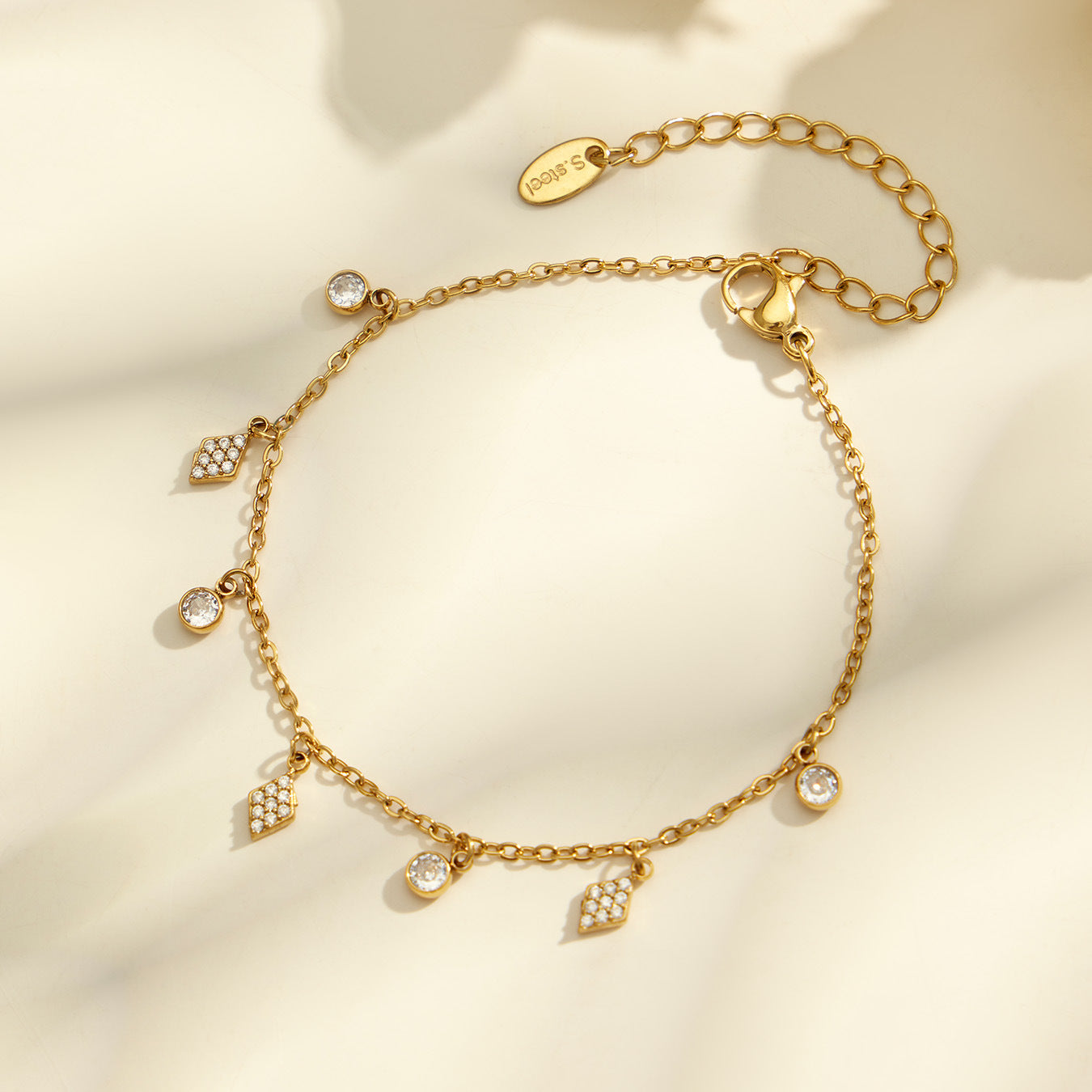 Flatlay of square, diamond and flower zircon charm bracelets with adjustable gold tone chain