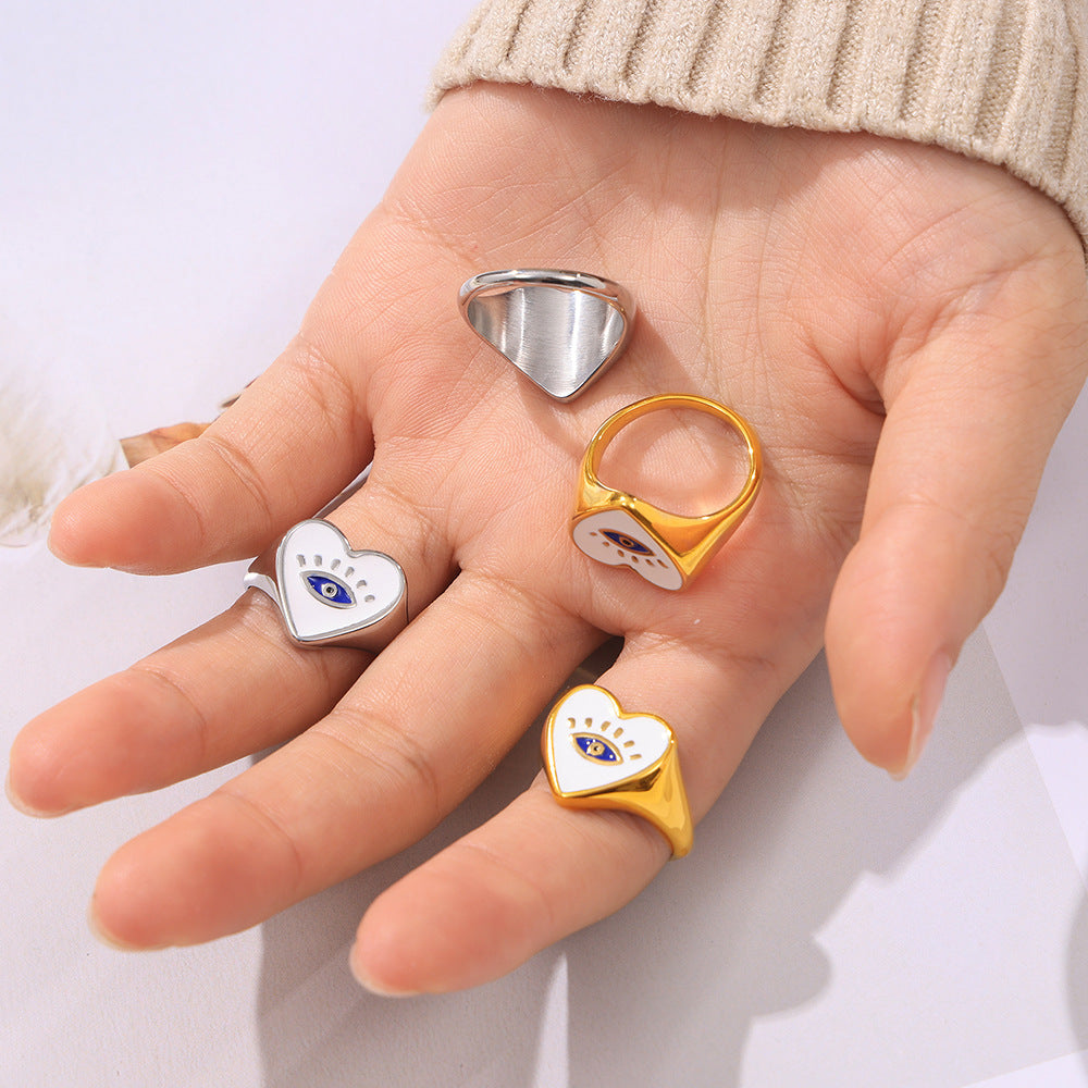 Close-up of a model wearing multiple evil eye heart rings in gold-tone and steel-tone finishes