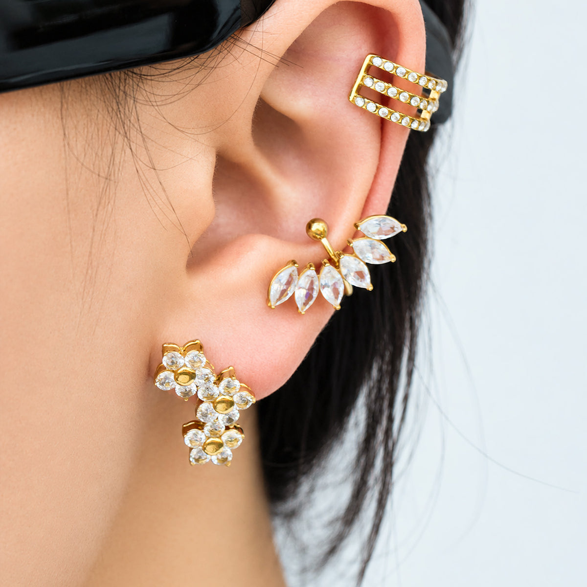 Side view of gold floral cluster earrings worn along the earlobe, showing three sparkling flower motifs