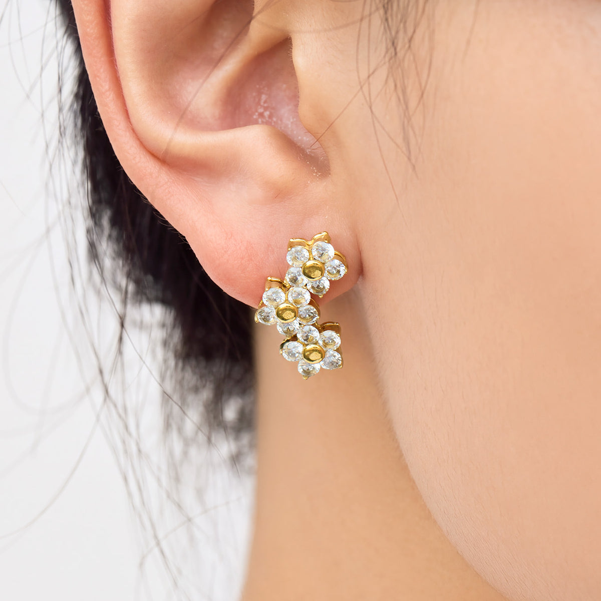 Gold flower cluster drop earring worn on the earlobe, highlighting the cascading arrangement of three five-petal flowers