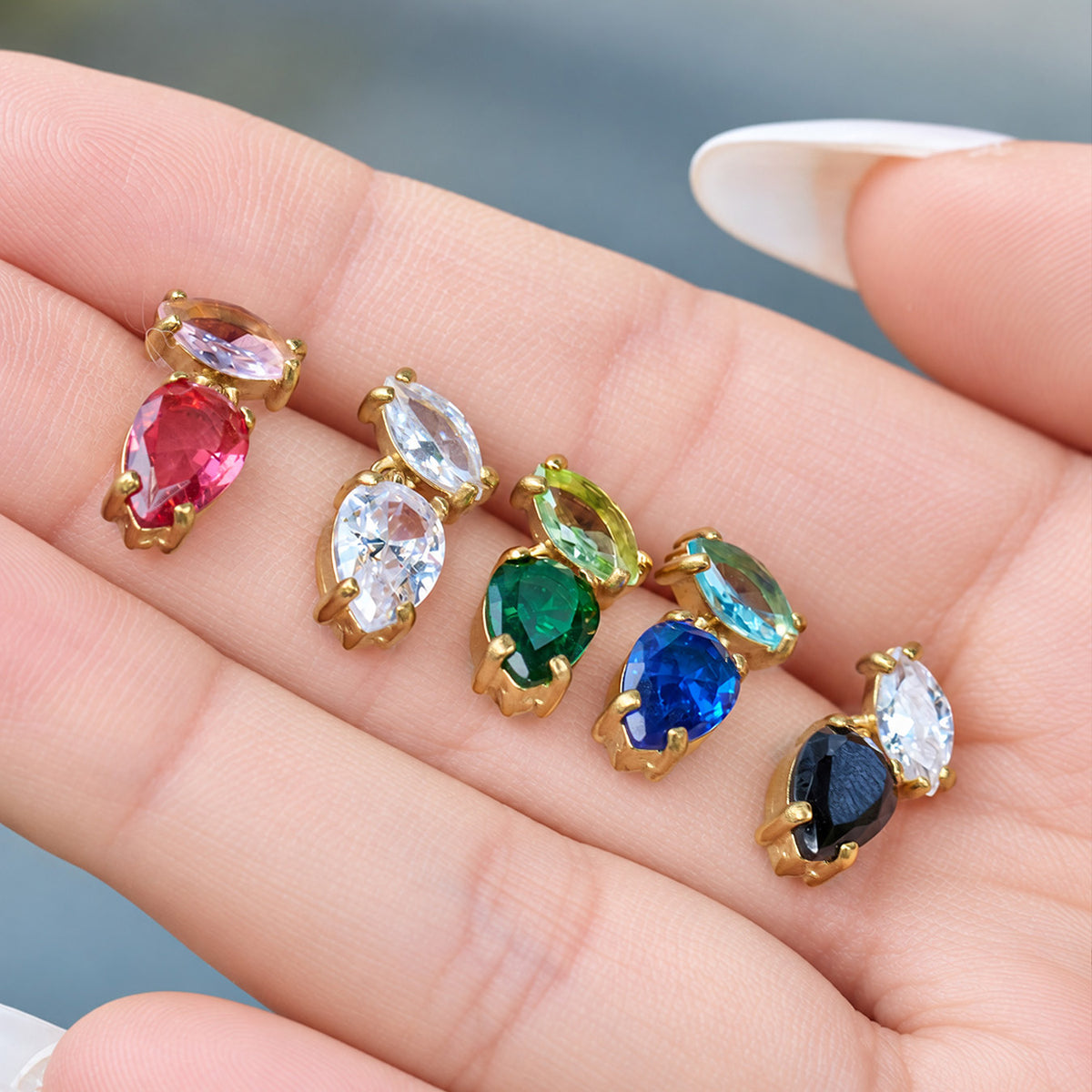 Hand display of F975 zircon drop earrings in red, clear, green, blue and black for a colorful boutique assortment