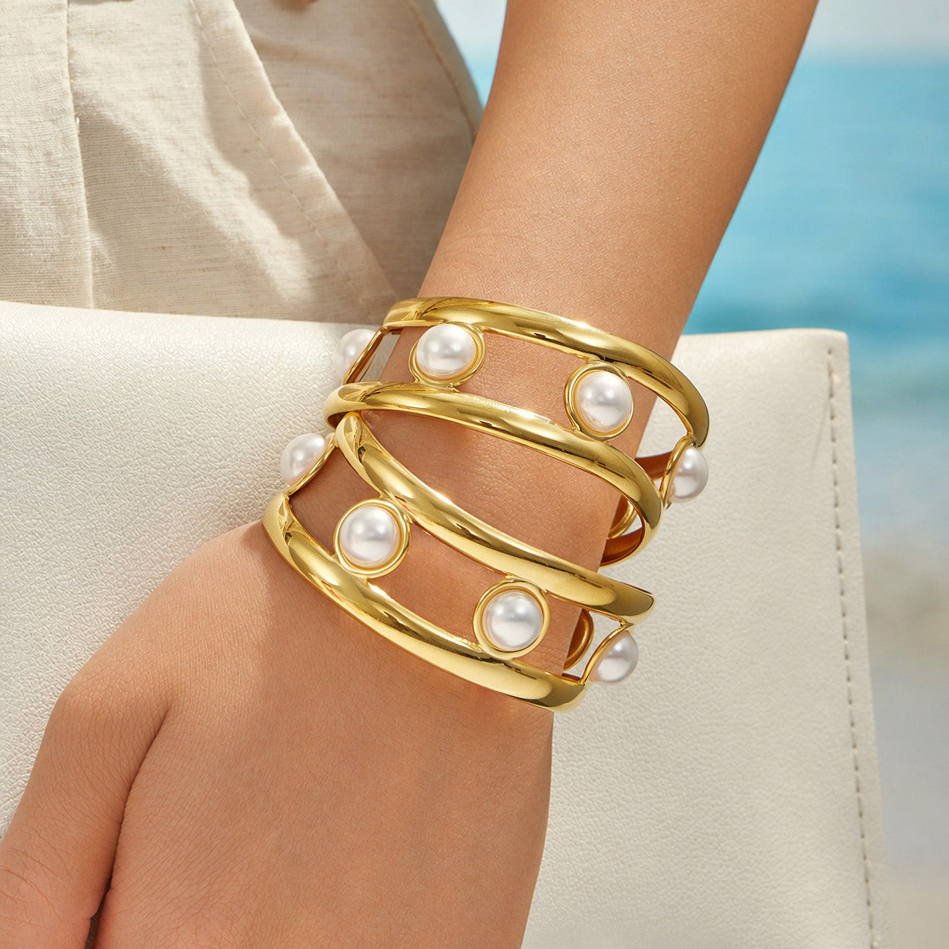 Faux pearl statement cuff bracelet worn on a model wrist against a blue background