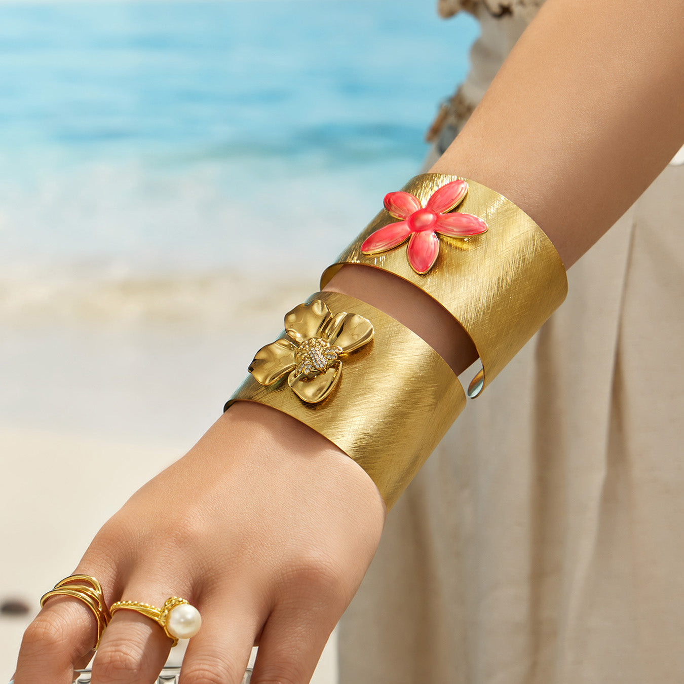 Model wearing bee and pink enamel flower cuff bracelets with gold rings
