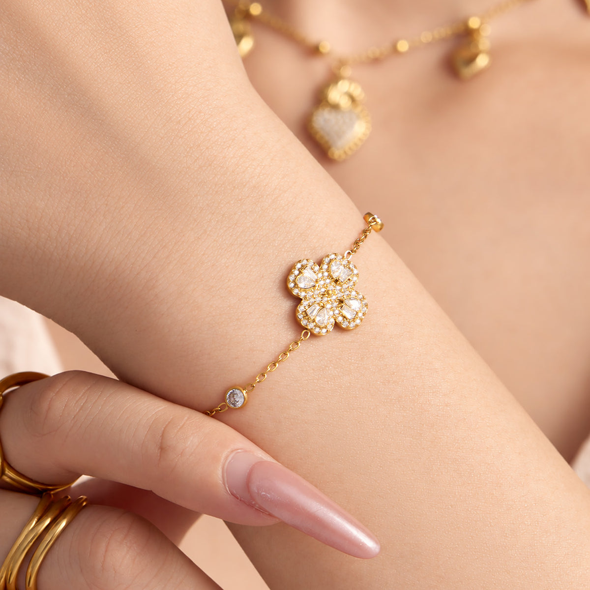 Gold-tone four-petal flower zircon bracelet worn on wrist with sparkling floral centerpiece