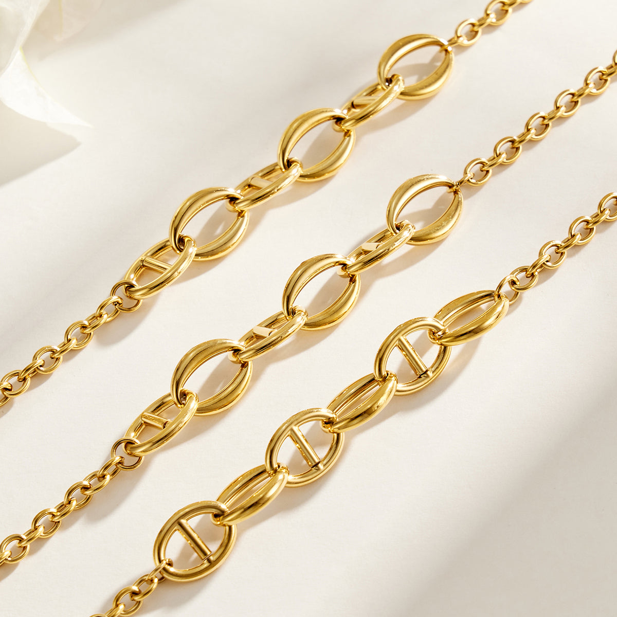 Close-up of gold geometric oval links on stainless steel necklace chain