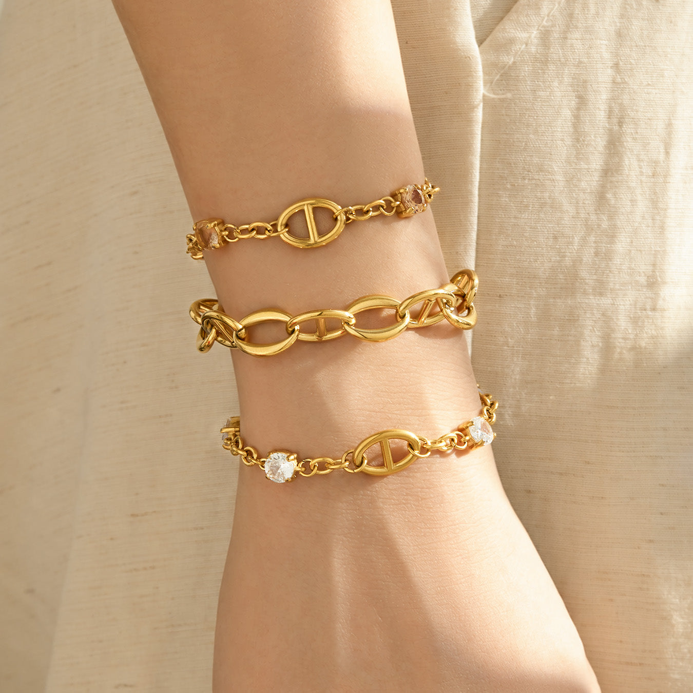 Gold oval link bracelets layered on the wrist in coordinating chain styles