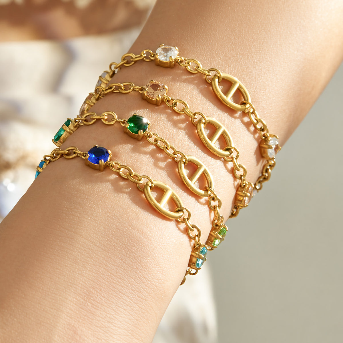 Gold oval link bracelets stacked with colorful zircon accents and chunky chain details