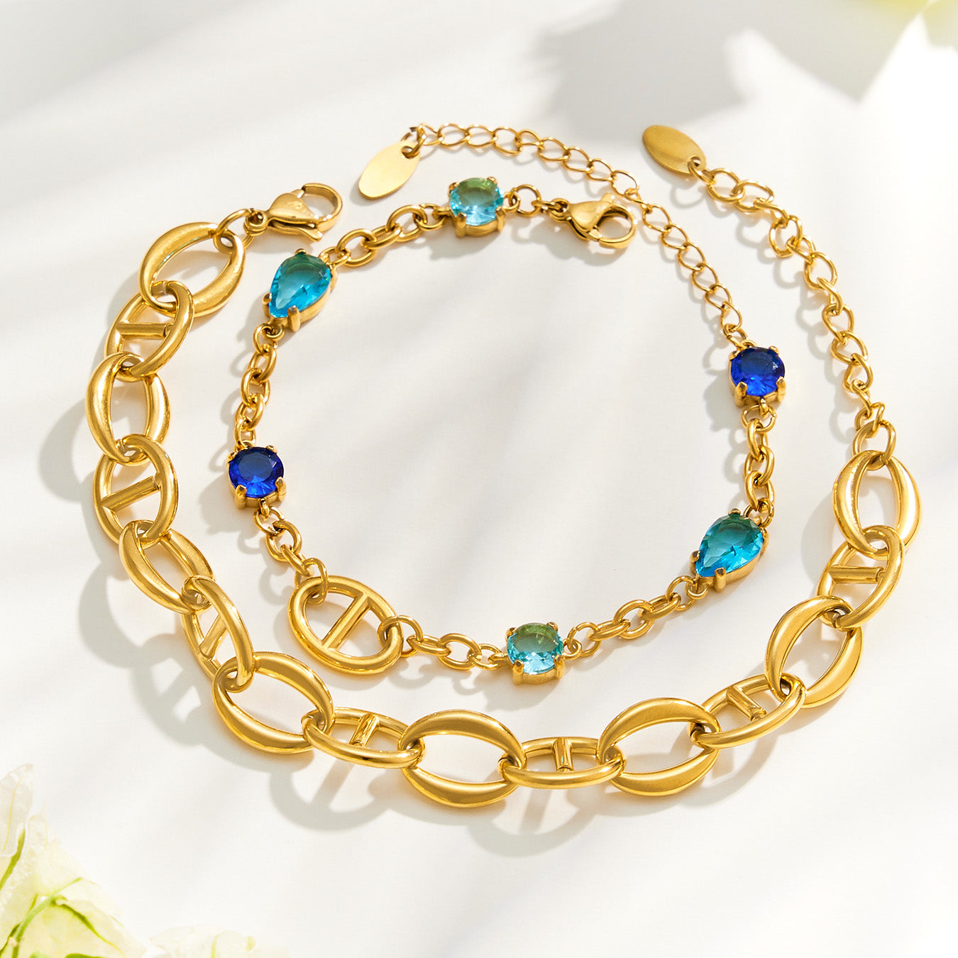 Plain and zircon-accented oval link bracelets displayed together in gold finish