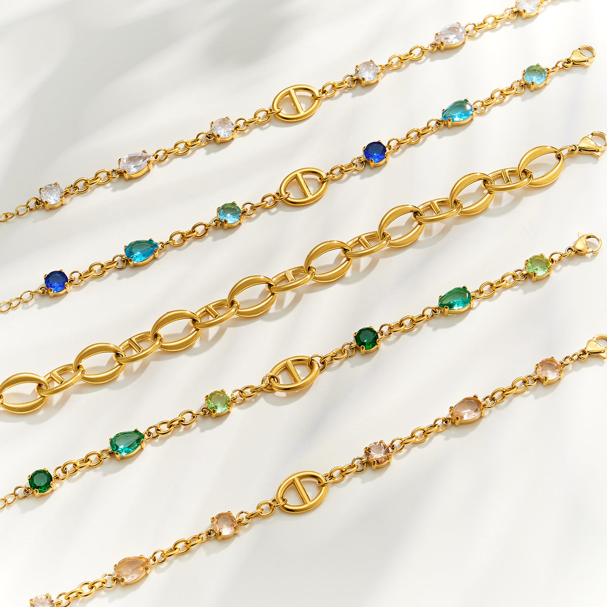 Gold oval link bracelet chains arranged in rows with plain and zircon-accented designs
