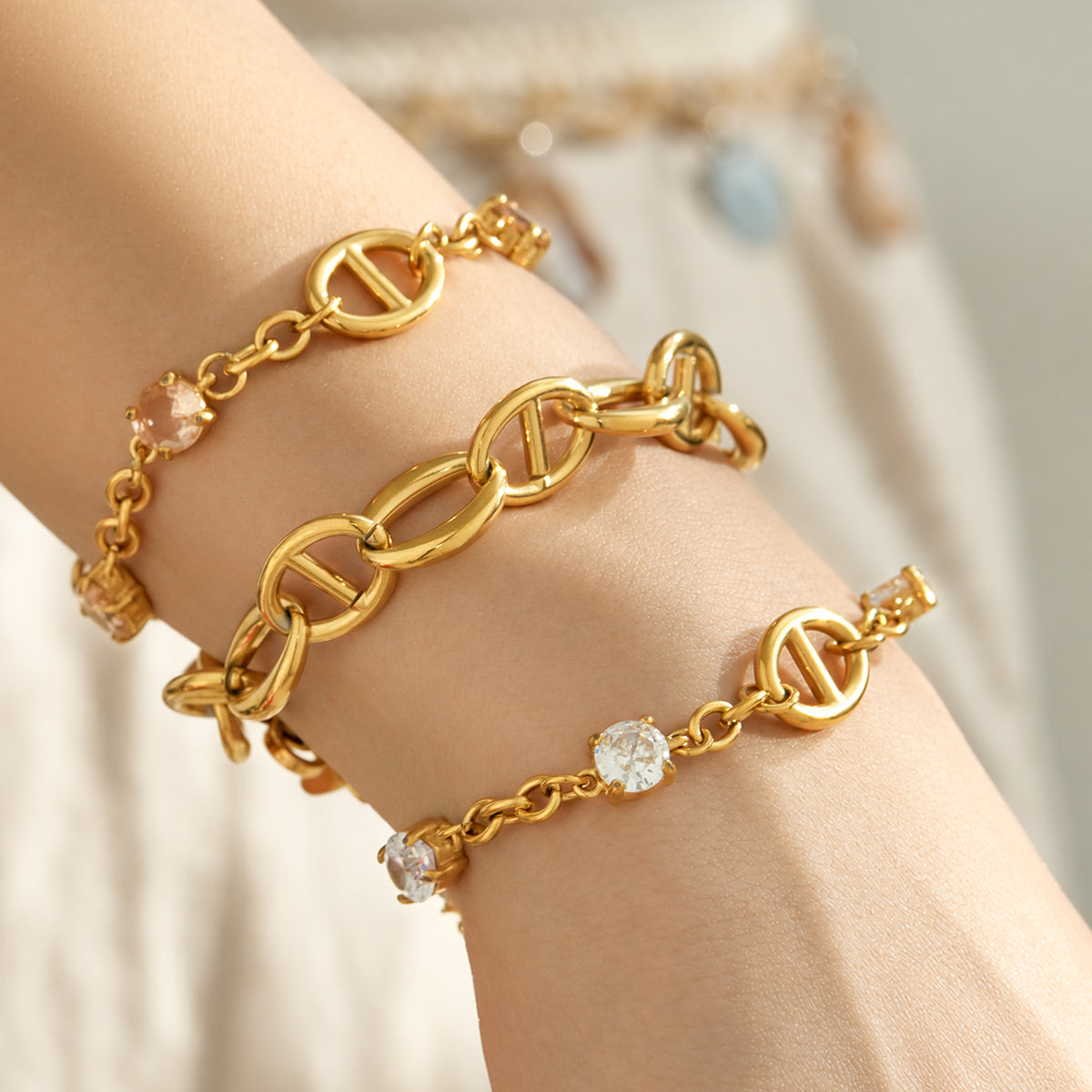 Plain gold oval link bracelets layered together on a model wrist