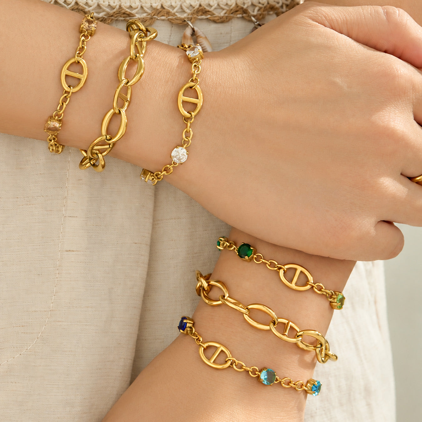 Gold oval link bracelets layered on both wrists with plain and zircon-accented styles